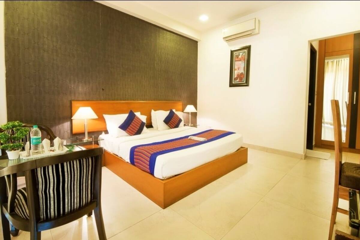 A hotel room with a bed, bedside lamps, a desk, and a chair.