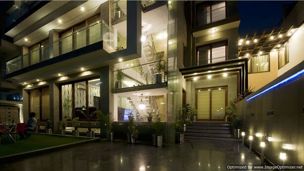 A modern multi-story building with a well-lit entrance, outdoor seating area, and visible balconies.
