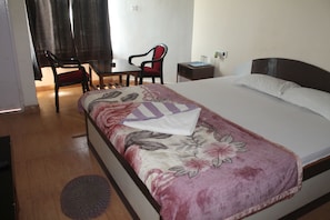 A hotel room with a bed, a desk, a chair, and a small table. - Arya Beach Resort (Kanthi)