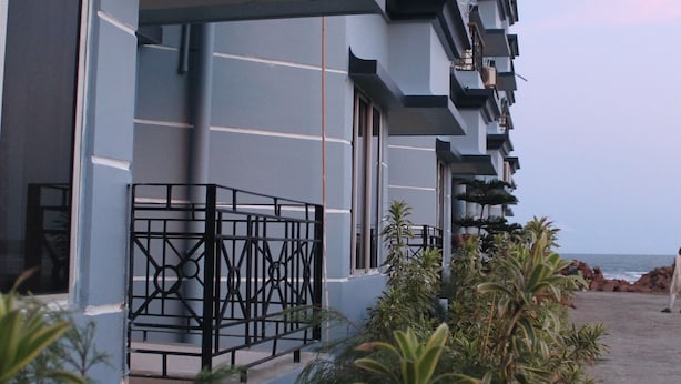 Um hotel moderno com várias varandas, um caminho pavimentado e vegetação exuberante.