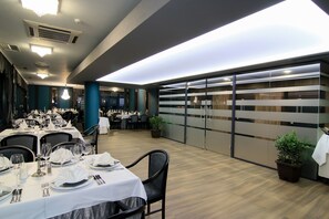 A restaurant with tables set for dining, potted plants, and a modern interior design.