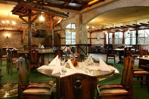A restaurant with rustic stone walls, wooden furniture, and a central dining table set for four.