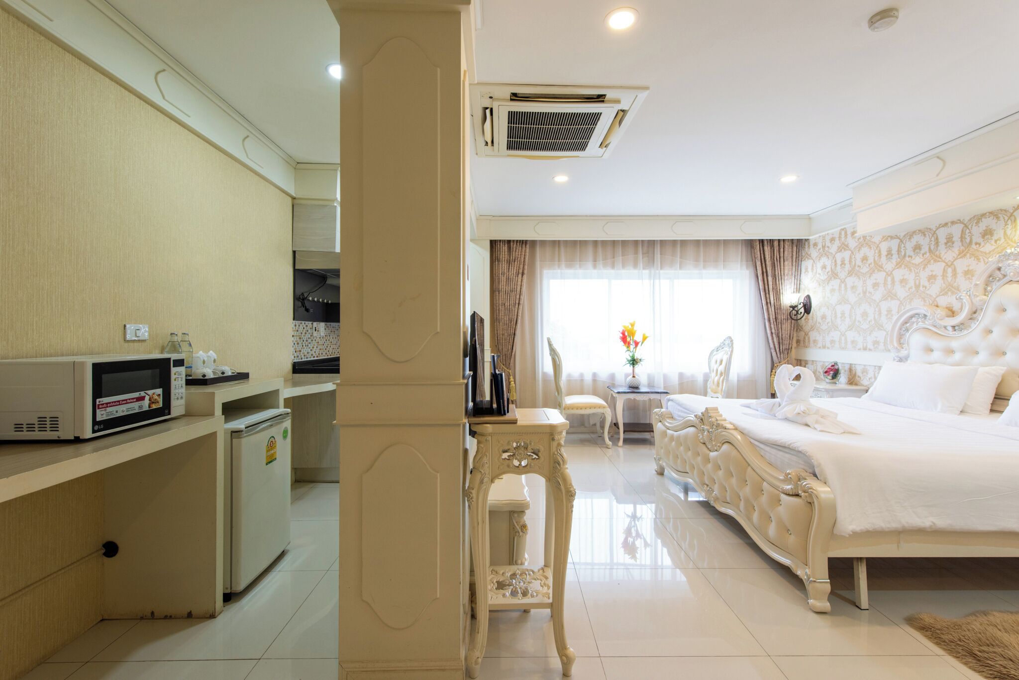 Habitación de hotel con cama, una kitchenette pequeña, zona de comedor y vistas al exterior.
