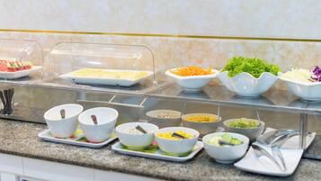 A buffet with various food items in bowls and a covered section.