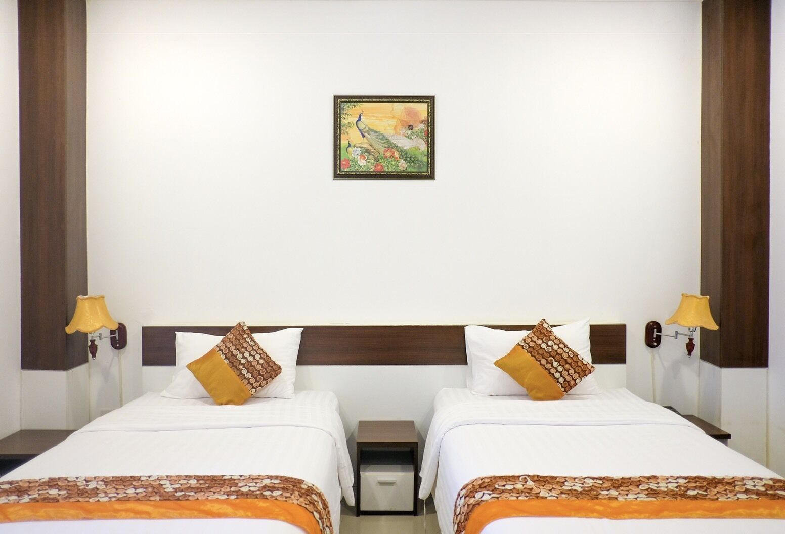Une chambre d’hôtel avec deux lits, une table de chevet, une lampe et un tableau au mur.