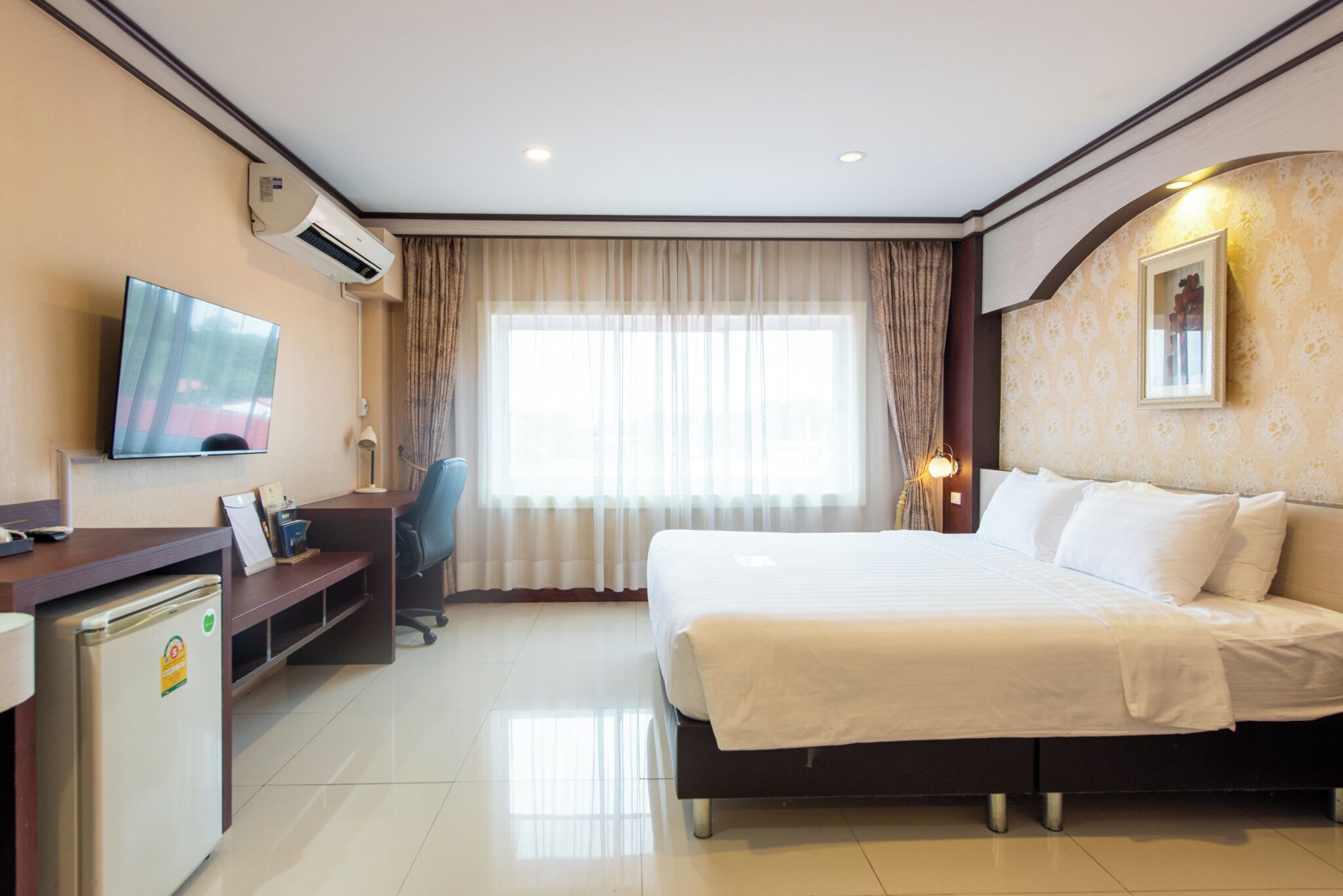 Een hotelkamer met een bed, bureau, stoel, televisie en airconditioning.