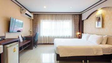 Quarto de hotel com cama, escrivaninha, cadeira, televisão e ar condicionado.