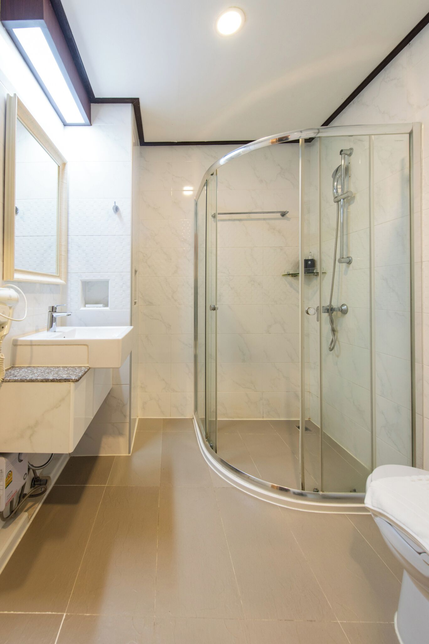 A modern bathroom with a glass-enclosed shower, a white sink, and a mirror.