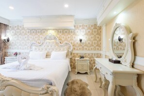 Un dormitorio lujoso con una cama grande, un tocador ornamentado y un espejo.