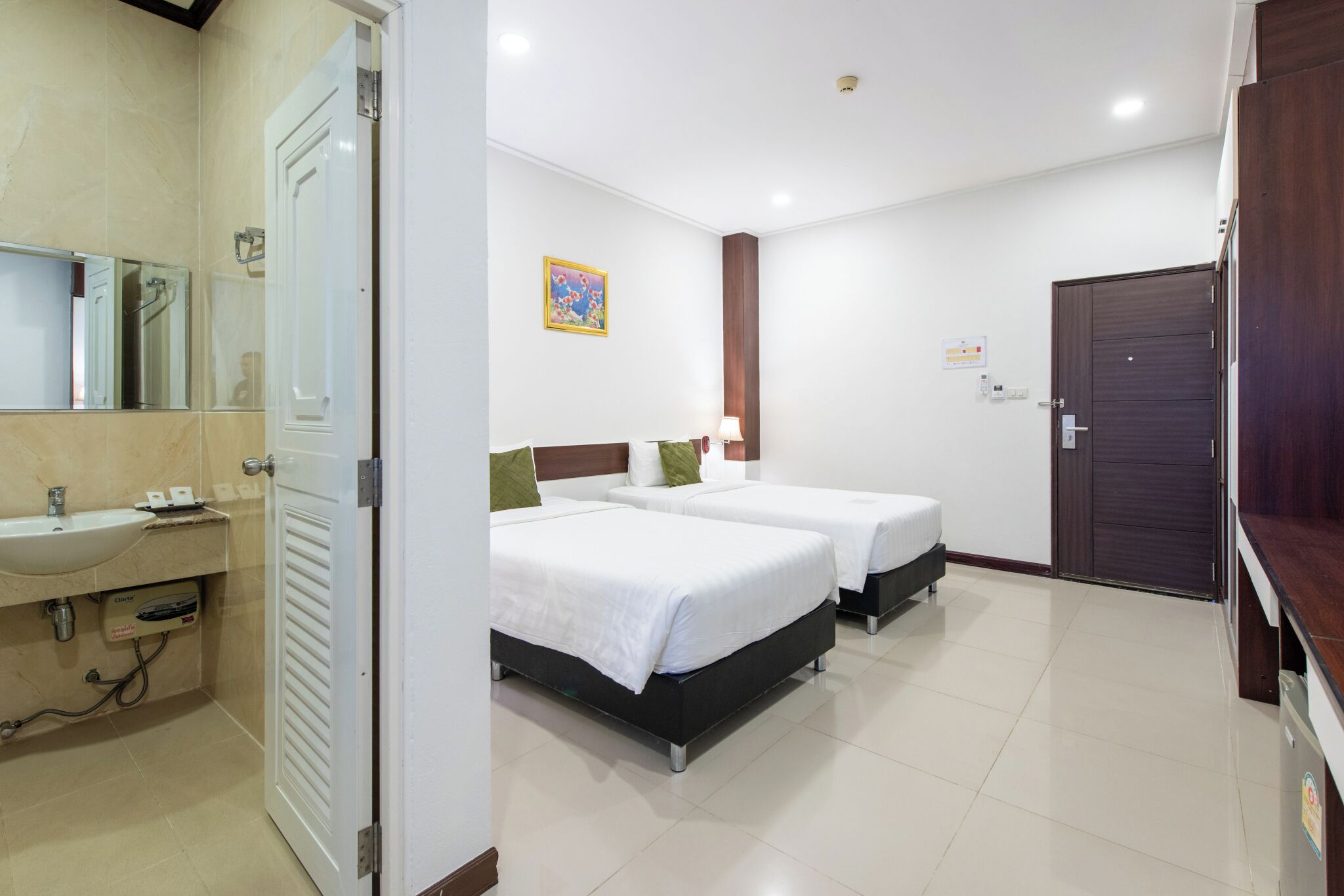 A hotel room with two beds, a sink, and a mirror.