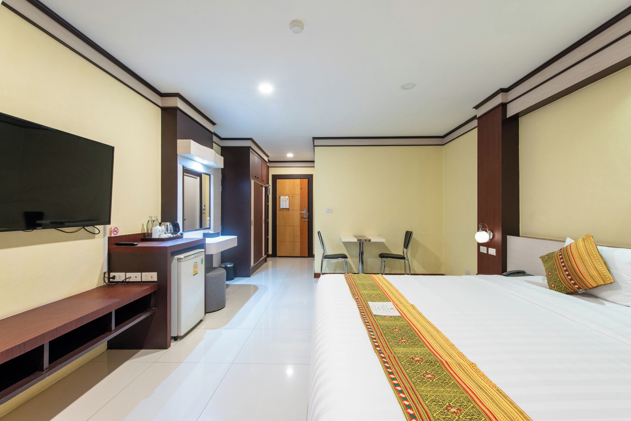 A hotel room with a bed, a desk, a television, a small kitchenette, and a bathroom.
