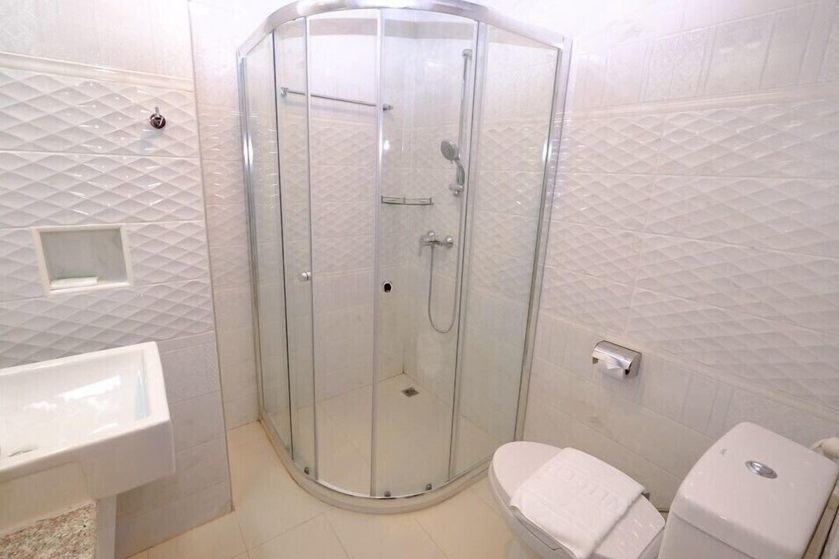 A modern bathroom with a glass-enclosed shower, a white sink, and a toilet.