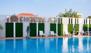 Una piscina con sillas de descanso y una escultura de delfín.