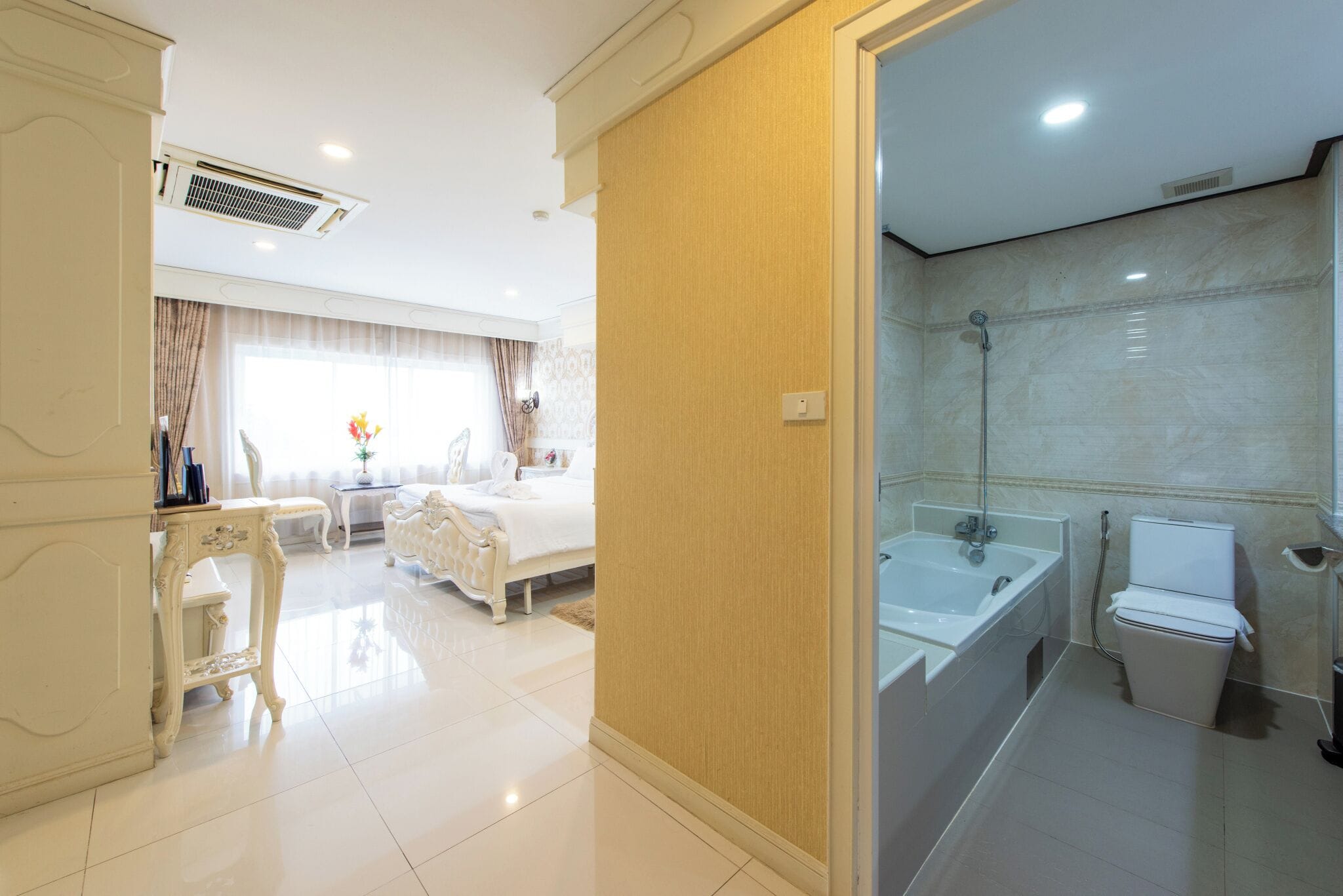 Ein Hotelzimmer mit Bett, Nachttisch und einem Badezimmer mit Badewanne und Toilette.