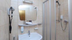 A bathroom with a sink, mirror, hairdryer, and shower. - Hotel Reischenau (Ustersbach)
