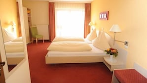 A hotel room with a bed, bedside lamps, a chair, a small table with a vase, and a window with curtains. - Hotel Reischenau (Ustersbach)