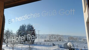 A view from a window at Hotel Reisenau, featuring a snowy landscape with trees and a clear sky. - Hotel Reischenau (Ustersbach)