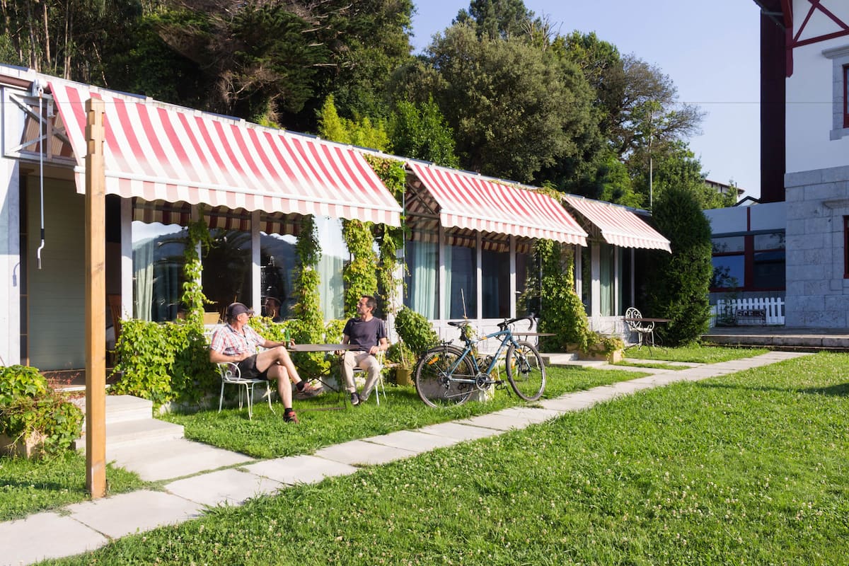 A building with a red and white striped awning, a bicycle parked outside, and a pathway leading to the entrance.