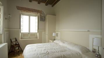 Un dormitorio con una cama, una ventana, una escalera y una mesita de noche con una lámpara.