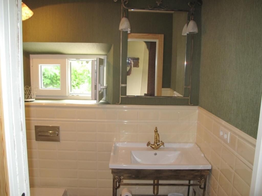 A bathroom with a white sink, a mirror, and a window.