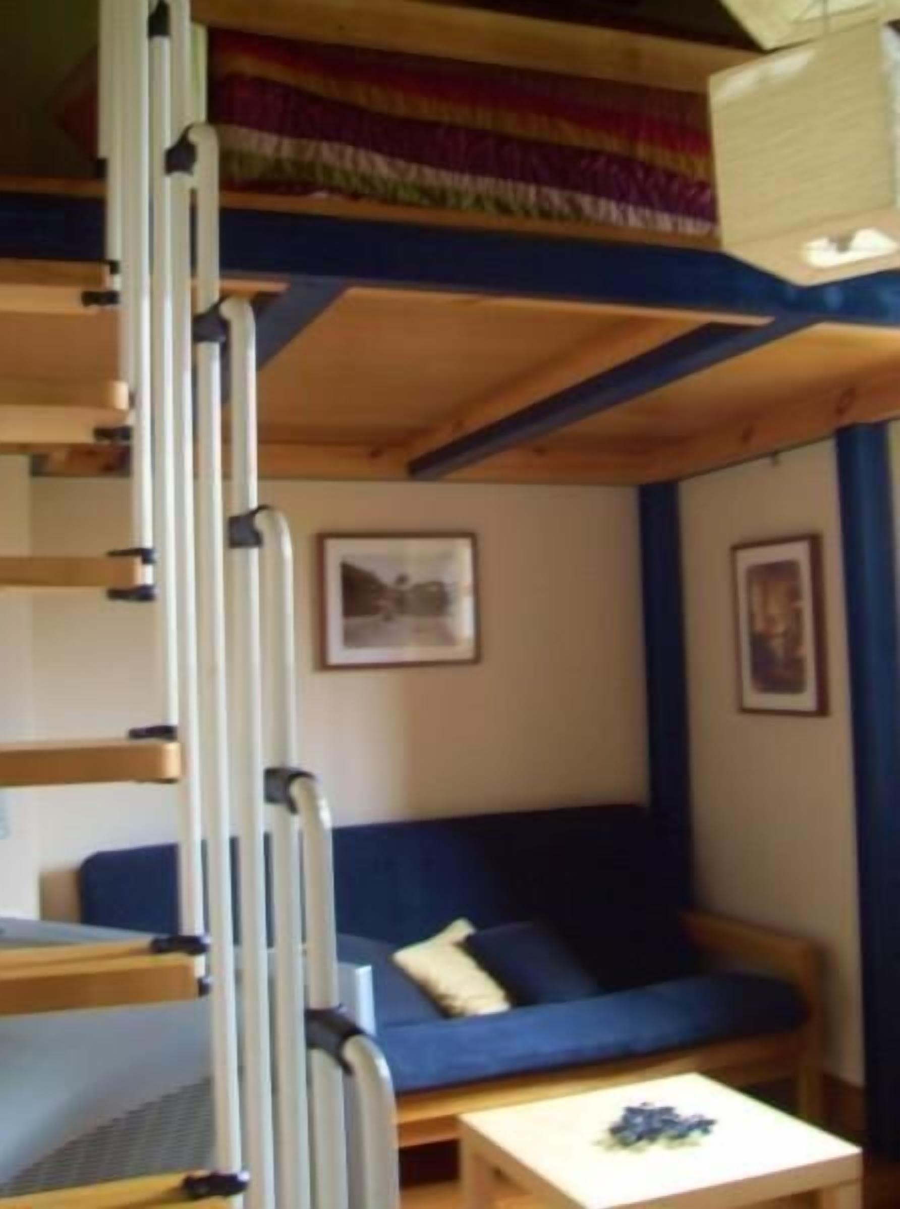 Camera con letto a castello, divano blu e un tavolino.