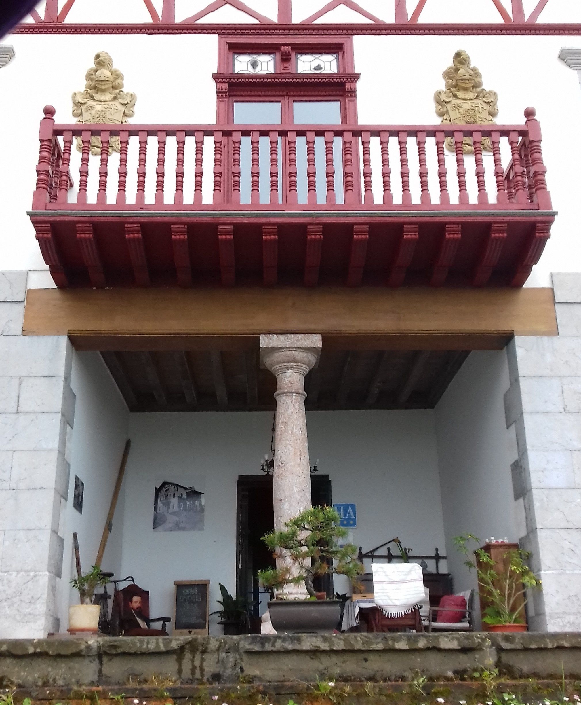 A building with a balcony, a central column, and a sign with a star.