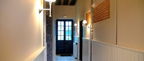A hallway with wooden flooring, white walls, and a black door at the end.