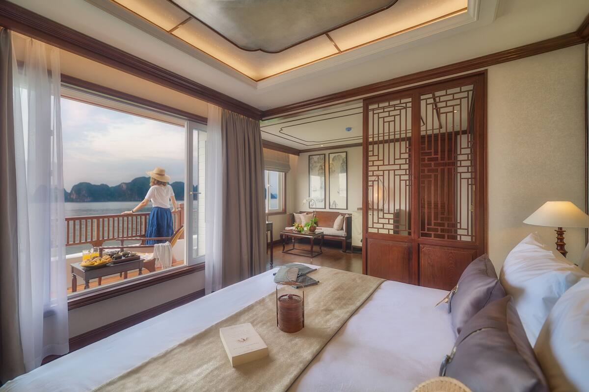 Ein Hotelzimmer mit einem großen Bett, Meerblick, einer Essecke mit Tisch und Stühlen sowie einem traditionellen Holzwand.
