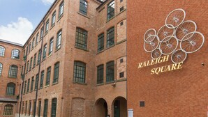 A brick building with multiple windows and a sign reading "Raleigh Square". - Raleigh Square Apartments (Nottingham)