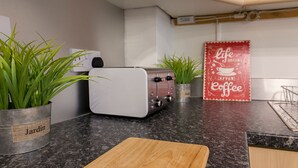 A kitchen with a toaster, two potted plants, a cutting board, and a 'Life After Coffee' sign. - Raleigh Square Apartments (Nottingham)