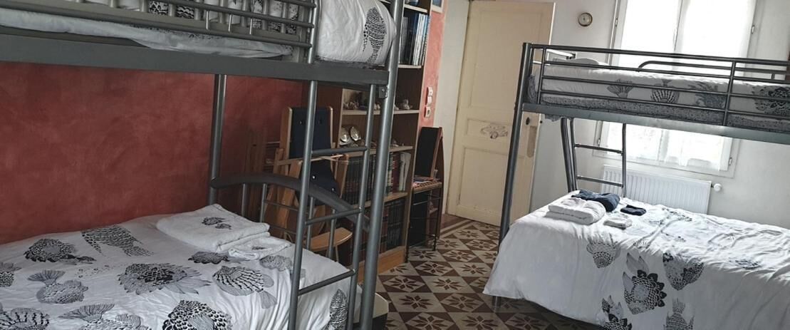 A dormitory room with bunk beds, a bookshelf, and a patterned floor.