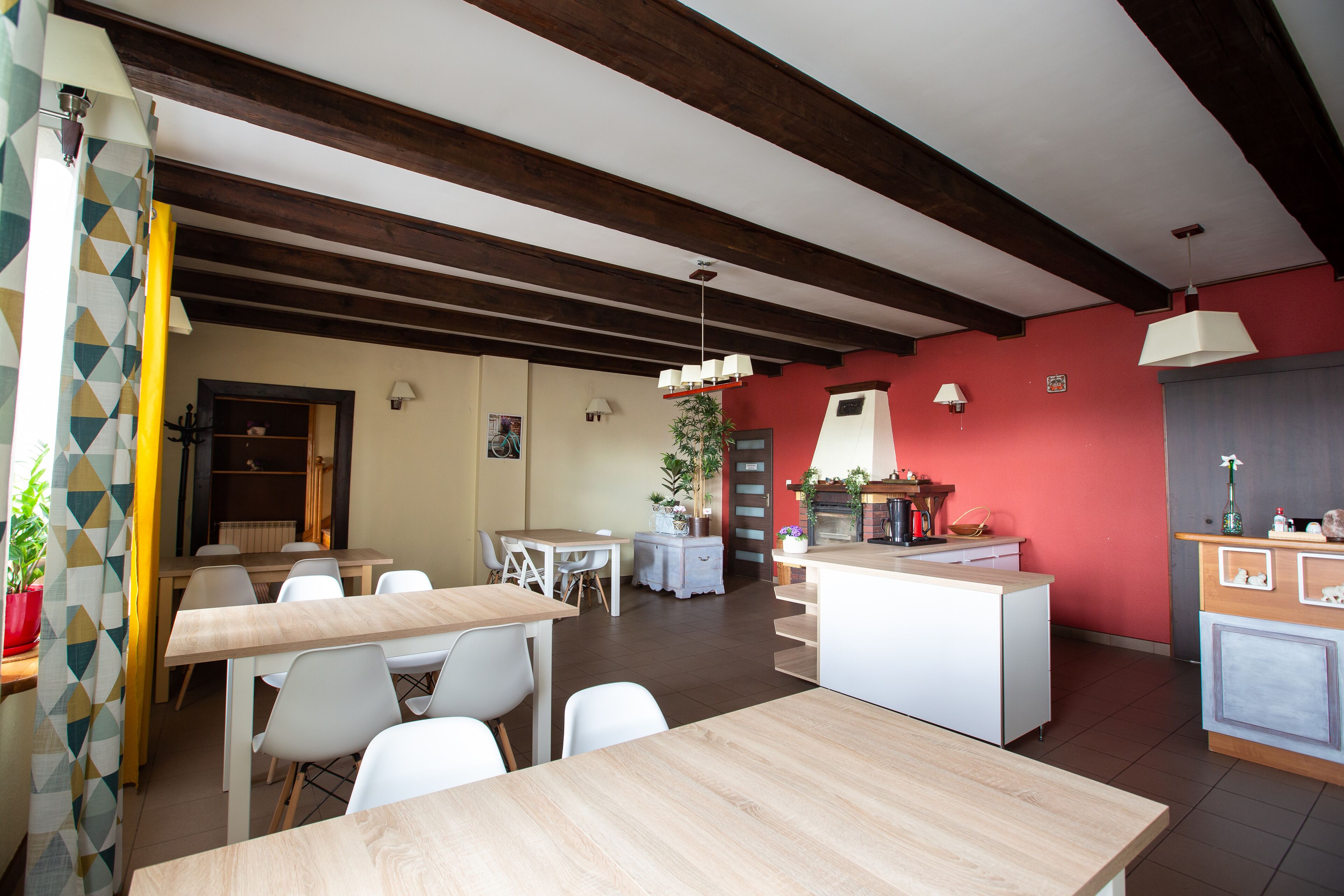 Een ruime keuken met een centraal eiland, houten balken in het plafond en een eethoek met witte stoelen en een tafel.