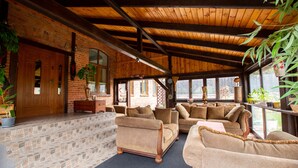 A cozy, rustic interior with stone steps leading to a seating area featuring sofas and armchairs.