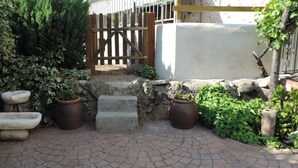 A paved patio area with stone planters, a wooden fence, and a stone wall. - Casa Rural Casona del Jerte (Jerte)