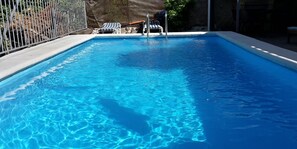 Una piscina al aire libre, tumbonas