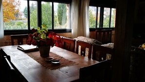 A dining table with a vase of red flowers, a placemat, and a book. - Casa Rural Casona del Jerte (Jerte)
