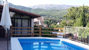 A swimming pool with a wooden deck and a view of mountains. - Casa Rural Casona del Jerte (Jerte)