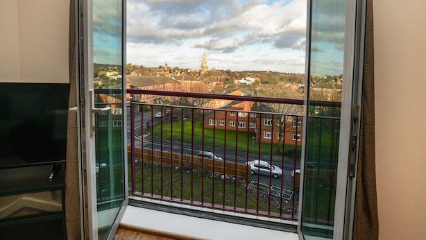 A room with a large window overlooking a street and a distant church. - Portland Square (Nottingham)
