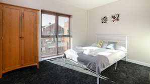 A bedroom with a bed, a wardrobe, a window with blinds, and two wall art pieces. - Portland Square (Nottingham)