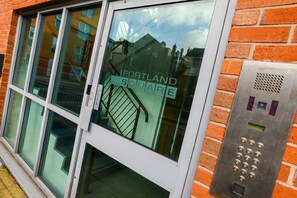 A building entrance with a glass door and a metal intercom system.