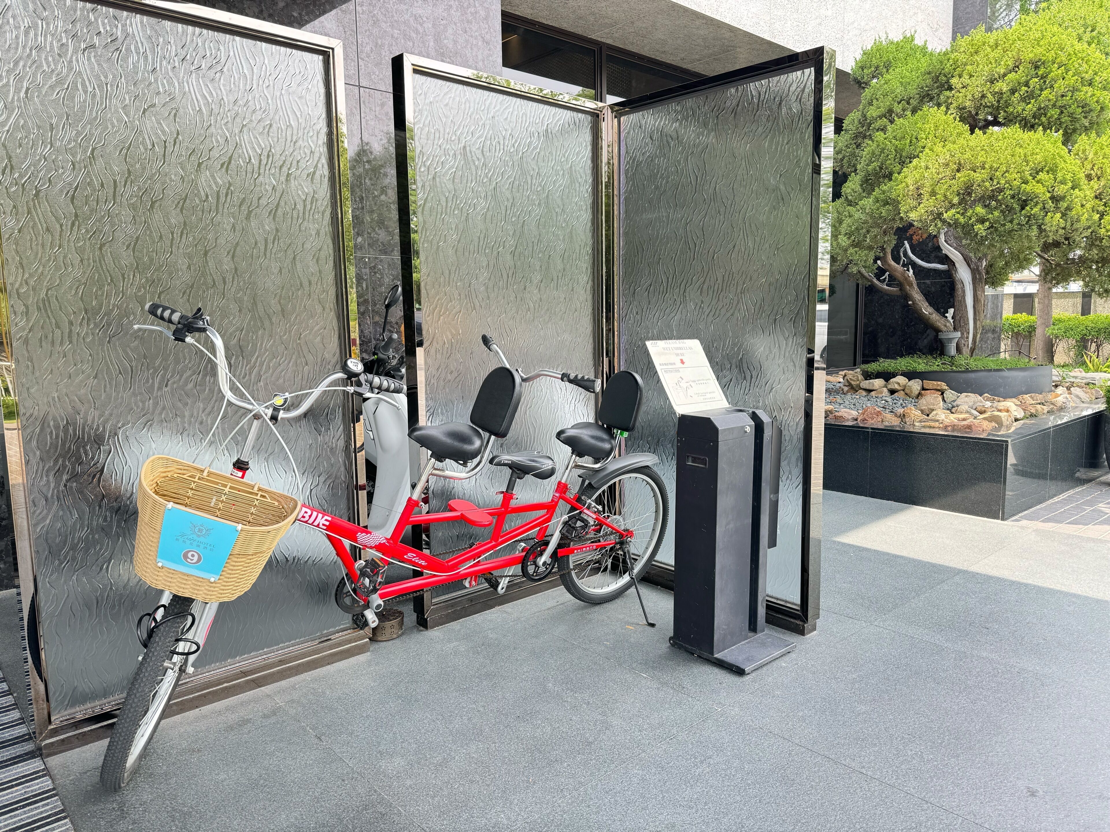A red bicycle parked in front of a building with a textured glass wall.