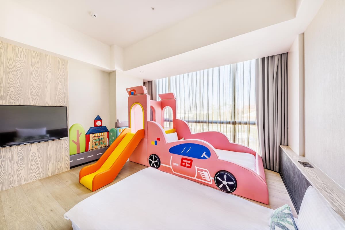 A children's play area with a slide and a playhouse, a flat-screen TV, and a large window with curtains.