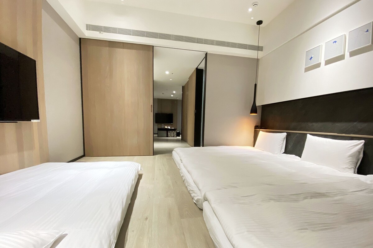 Una habitación de hotel con dos camas, televisión, escritorio y espejo.