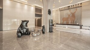 A modern lobby with a marble floor, a reception desk, and decorative bear sculptures. - Hsin Hotel (Chiayi City)
