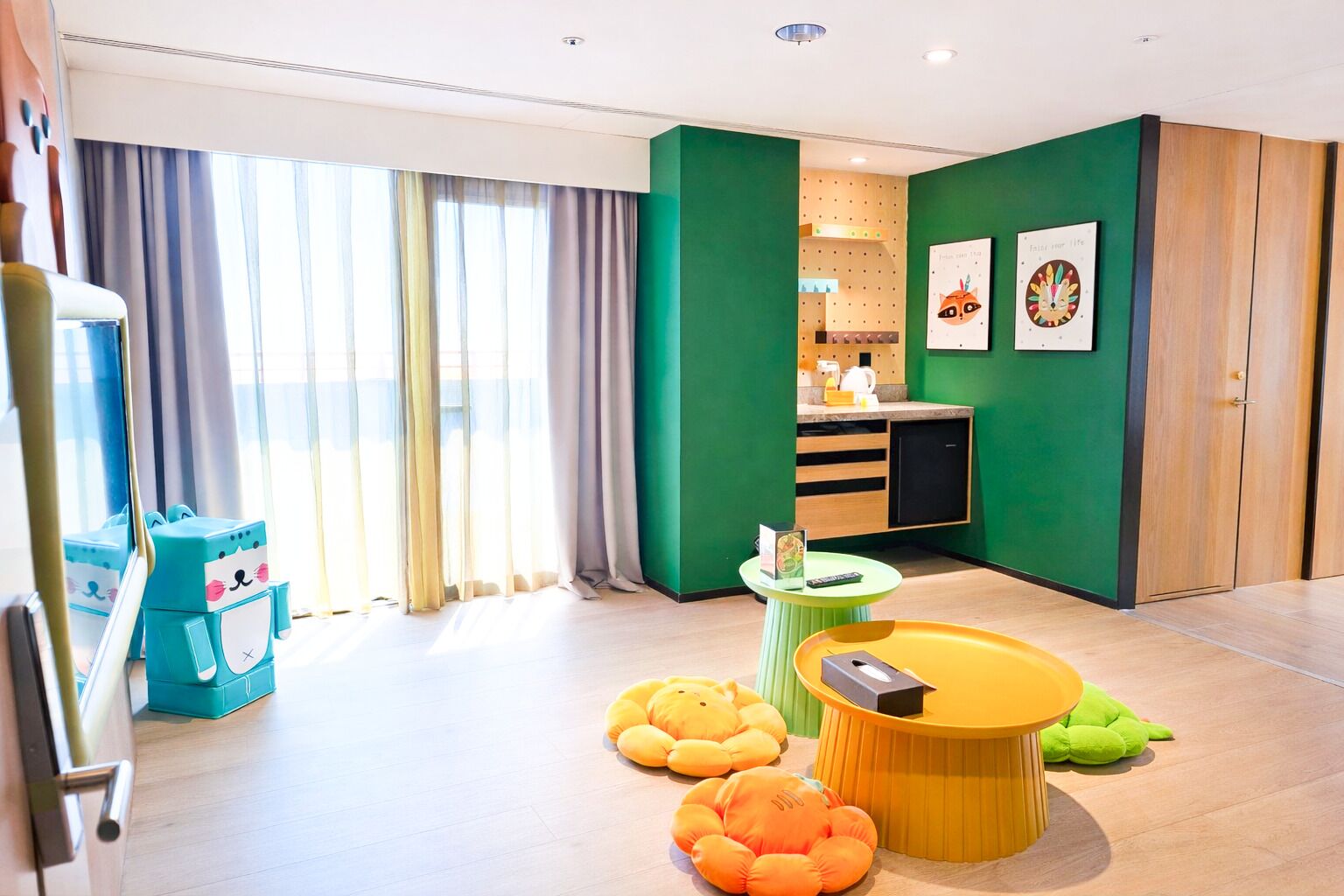 A modern hotel room with a kitchen area, a dining table, and a sofa.