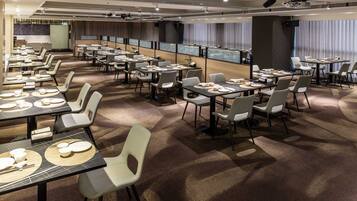 Een congreszaal met meerdere tafels en stoelen, voorzien van projectoren en een groot scherm.