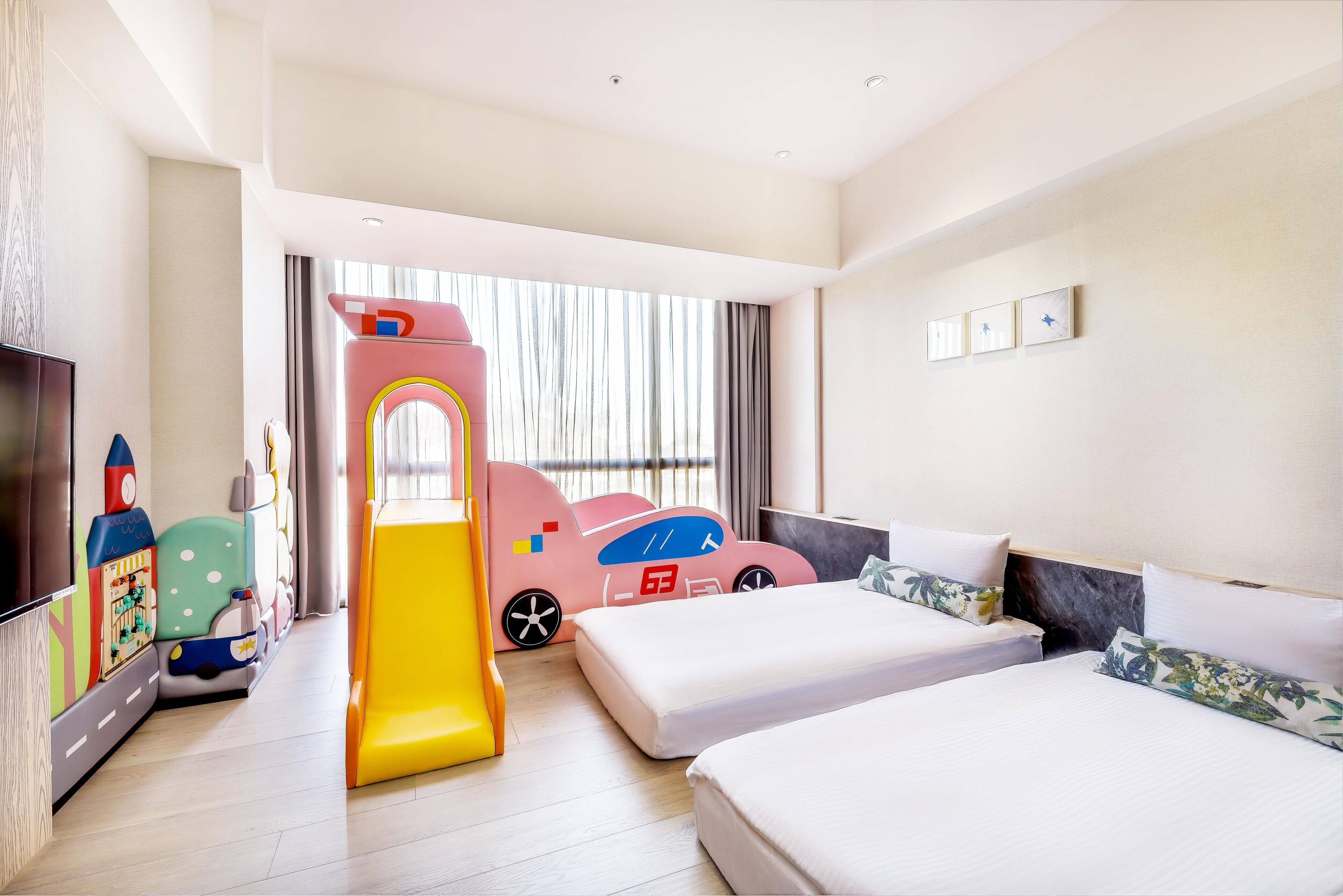 A hotel room with a bed, a play area with a slide, and a TV.