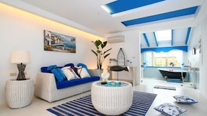 Una sala moderna con sofá, mesa de centro y vistas a un baño con bañera.