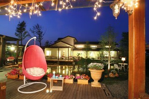 Eine Holzterrasse mit einer Hängematte, einem kleinen Tisch und Topfpflanzen.