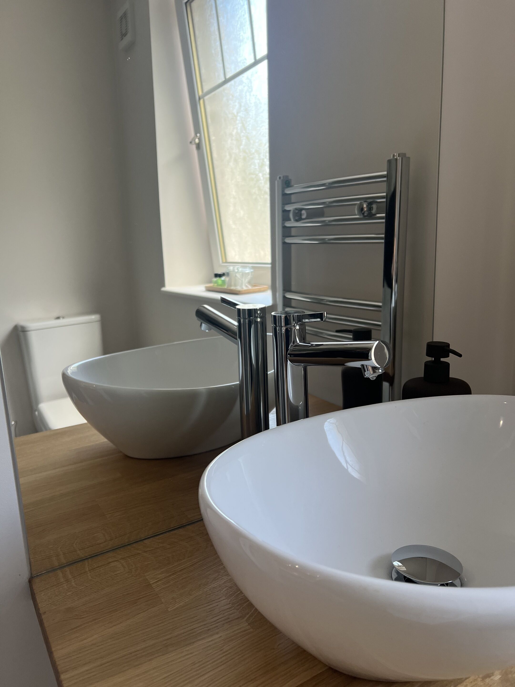 A bathroom with two white ceramic sinks, a chrome faucet, and a towel rack.